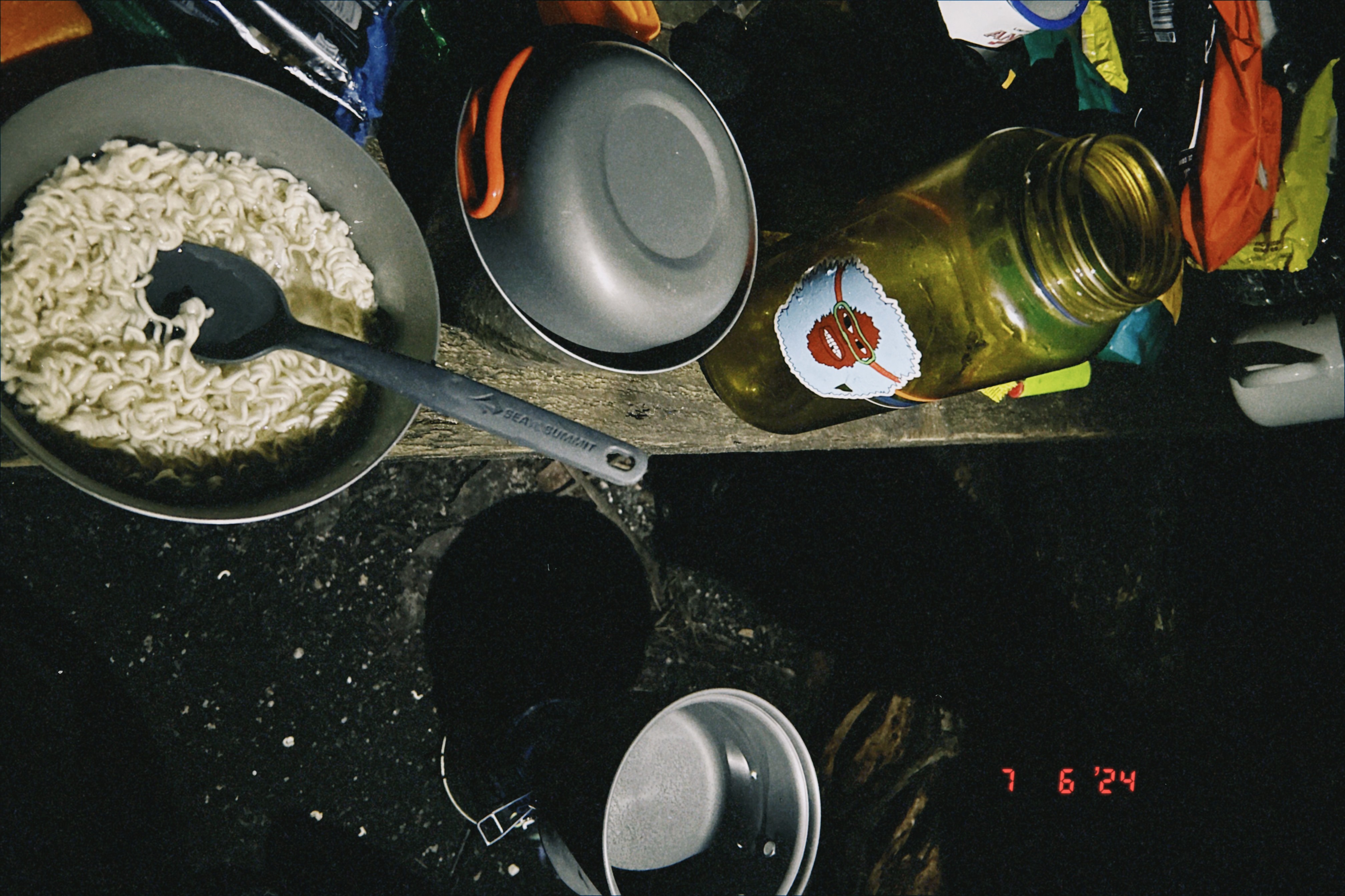 Trail cooking setup with noodles and gear at camp