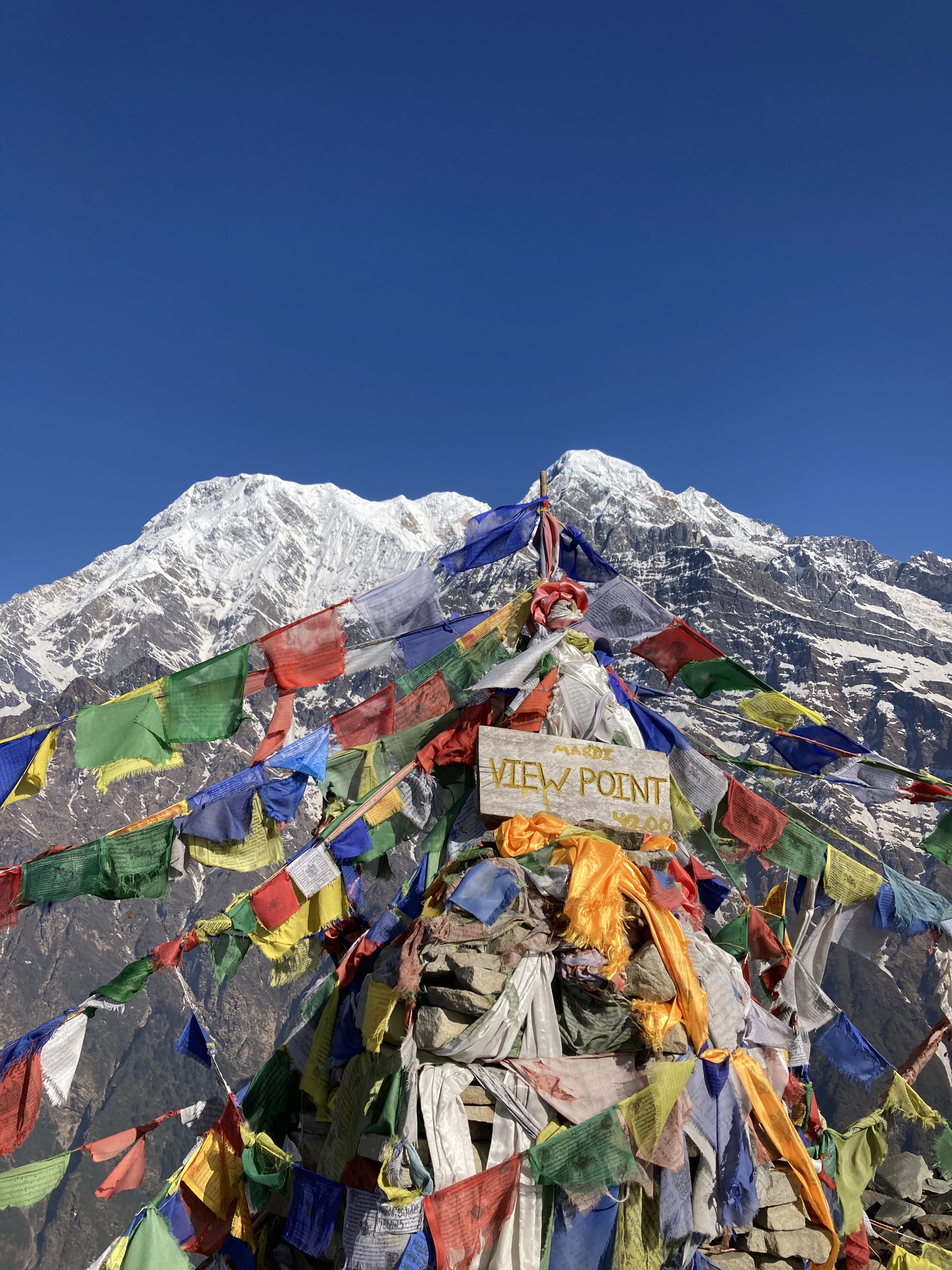 Colourful prayer flags at a mountain viewpoint with Annapurna behind