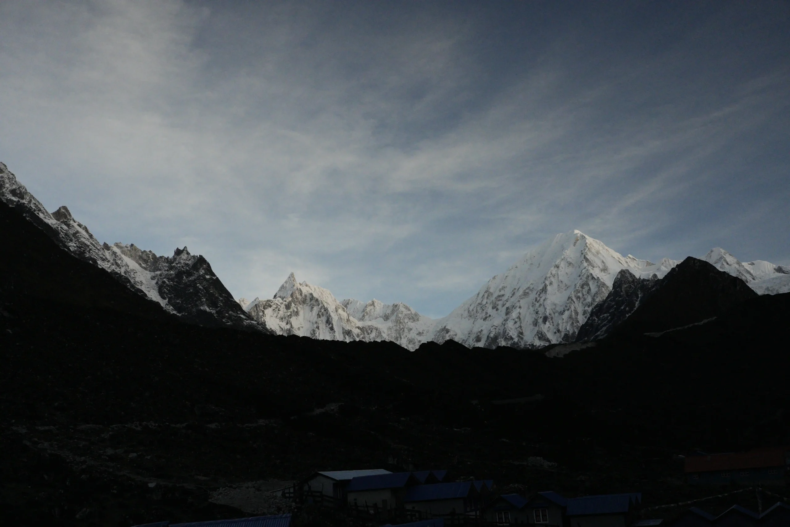 Snow-capped Himalayan peaks towering above a mountain lodge at dusk