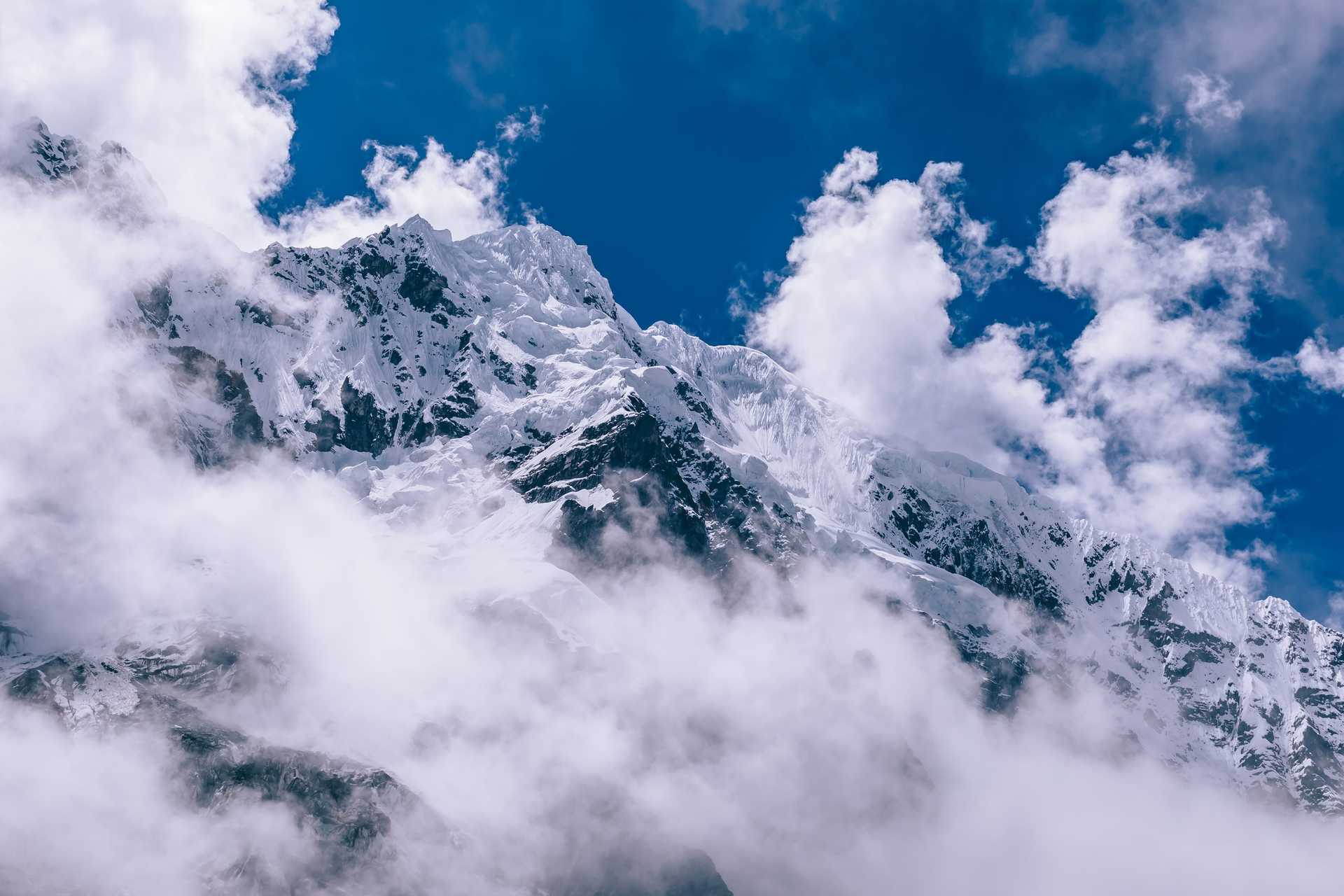 Dramatic snow-covered peak breaking through clouds