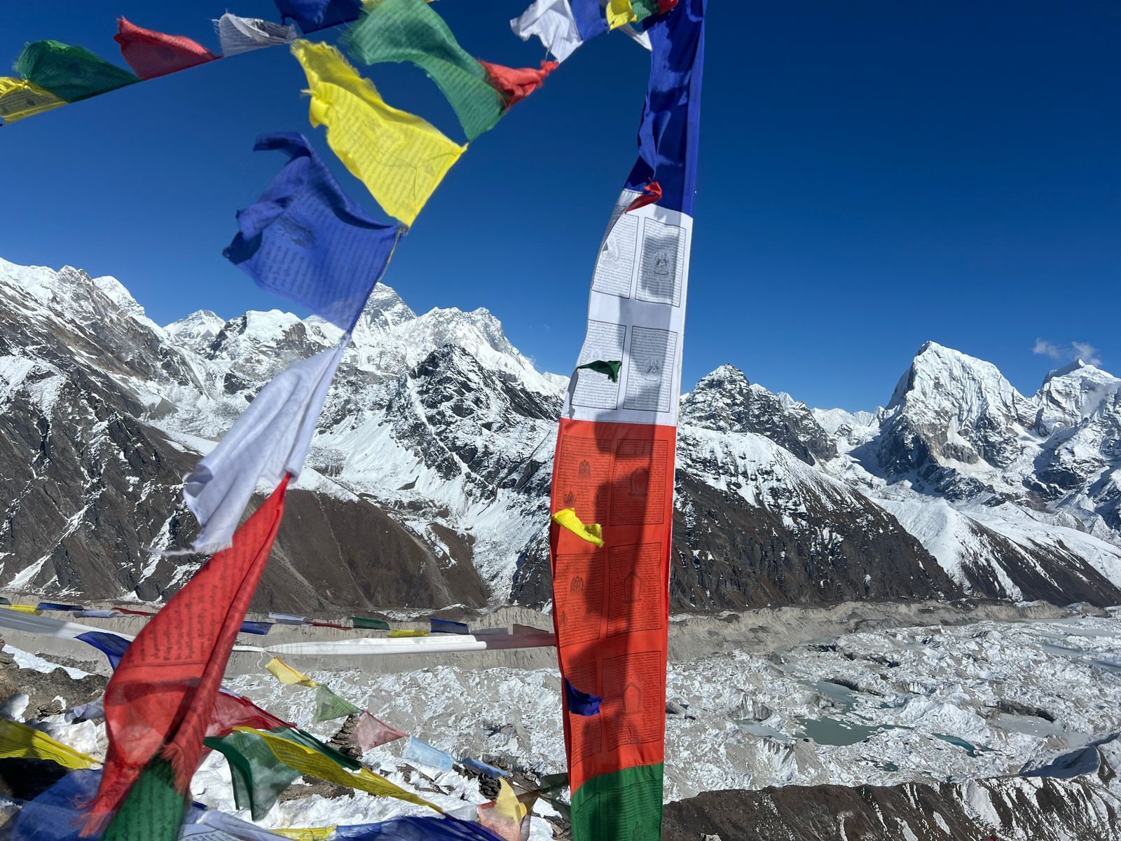 Prayer flags flying with Himalayan glacier panorama behind